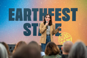 A fashion innovator holding a microphone and presenting strategy to attendees at an Earthfest summit event